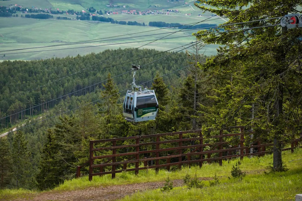 a cable car in the air above trees zlatibor